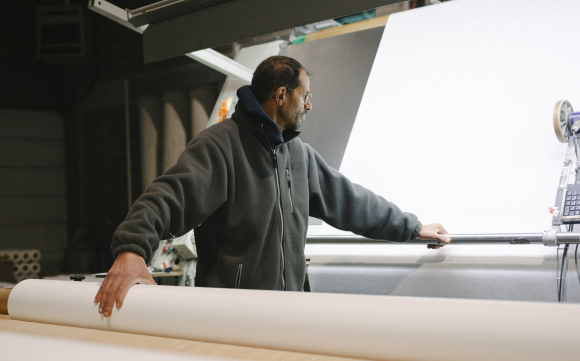 Expert in a textile manufacturing plant taking measurements of a technical fabric created by SUBRENAT on the basis of a specification.