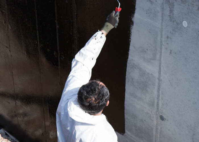 Professionnel du bâtiment appliquant une solution d'étanchéité verticale sur un textile SUBRENAT pour l'isolation du bâtiment 