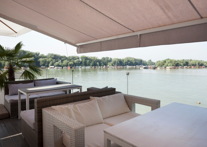 outdoor furniture on a covered terrace in front of a lake, with seat cushions made of Subrenat coated outdoor fabric