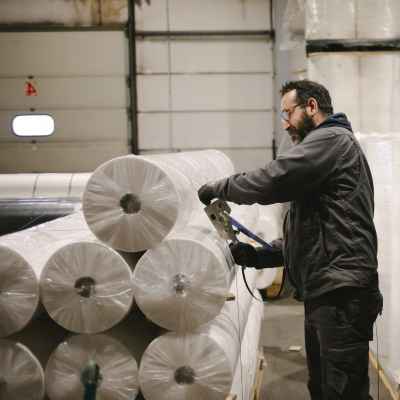 Conseiller SUBRENAT dans un entrepôt de logistique textile, livrant un rouleau de tissu conçu et fabriqué à la demande.